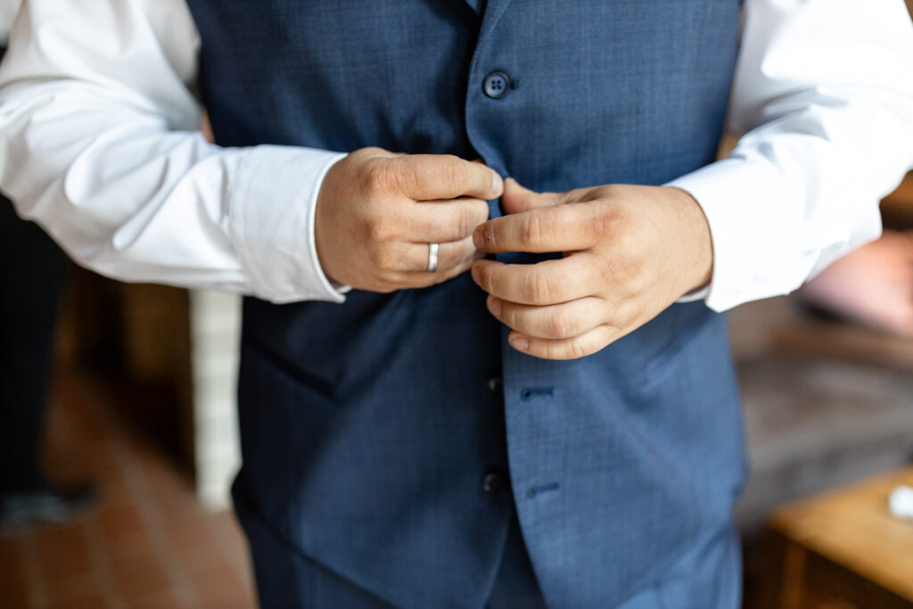 Detailaufnahme Getting Ready Bräutigam: Zwei Hände, wie dis gerade die Weste zuknöpfen.