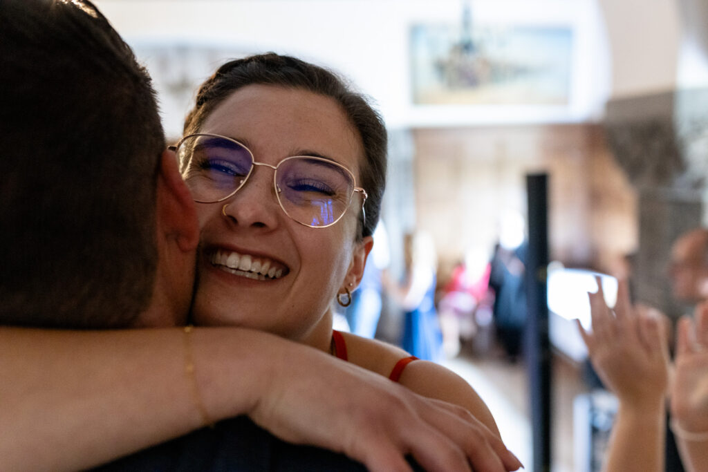 Trauzeugin Nahaufnahme, wie sie den Bräutigam nach einem Familien-Flashmob für das Paar in den Arm nimmt.