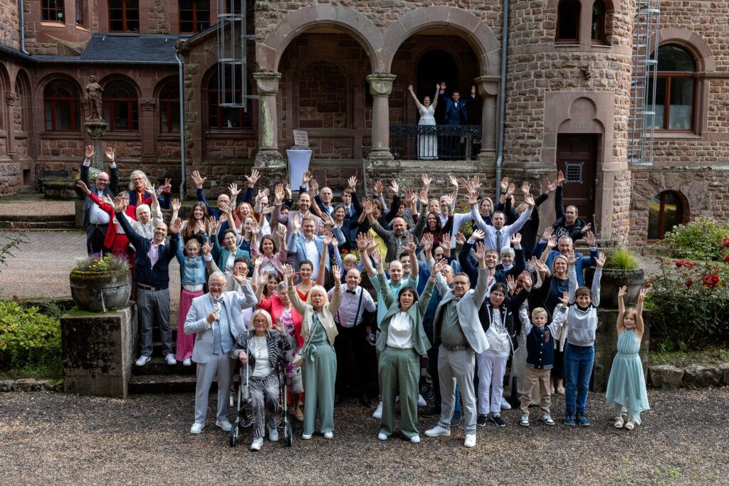 Gruppenfoto der gesamten Hochzeitsgesellschaft mit über 60 Gästen im Hof des Schloss, auf dem die Hochzeit gefeiert wurde.