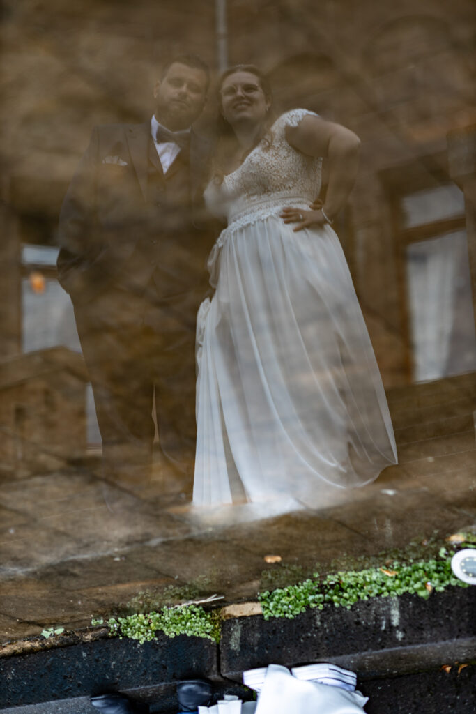 Brautpaar-Shooting im Freien in ungewöhnlicher Perspektive. Nach dem Regen wurde das Spiegelbild des Brautpaars in einer Pfütze fotografiert.