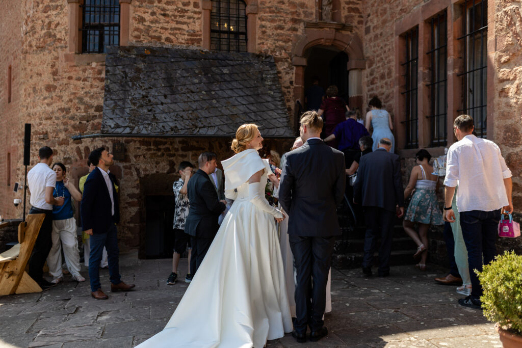 Die Hochzeitsgesellschaft versammelt sich und betritt die kleine Kapelle auf Schloss Hamm, während das Brautpaar vor der Treppe wartet.