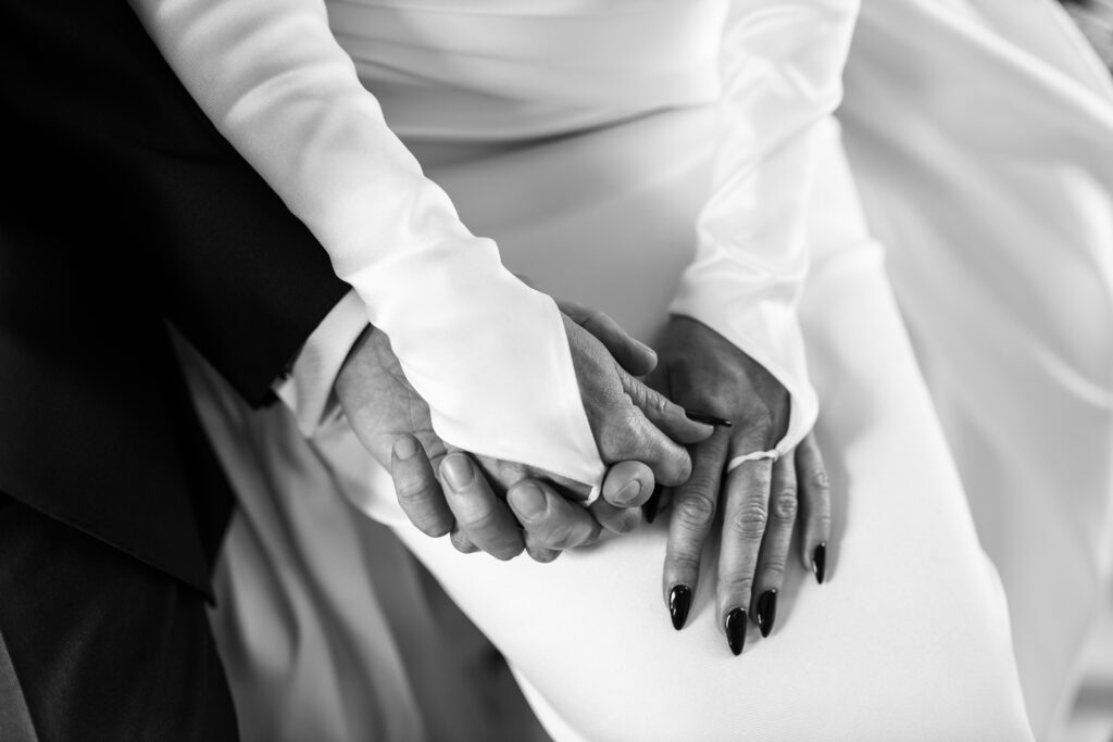 Schwarz-weiss Nah-Aufnahme, wie das Brautpaar Händchen hält.