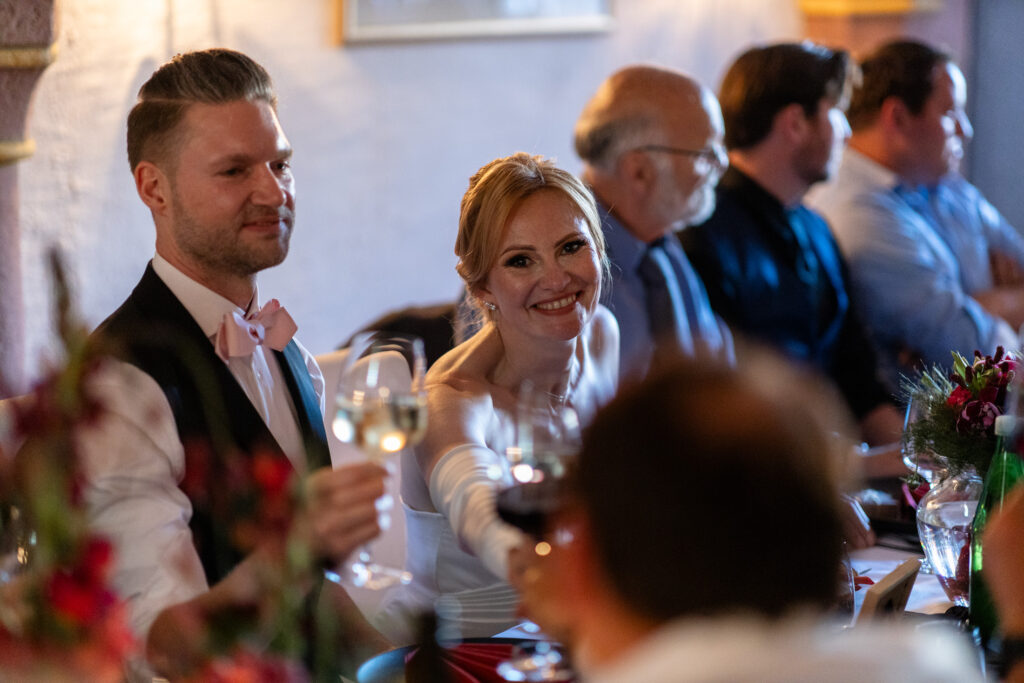 Die lächelnde Braut prostet beim Abendessen einem Gast zu