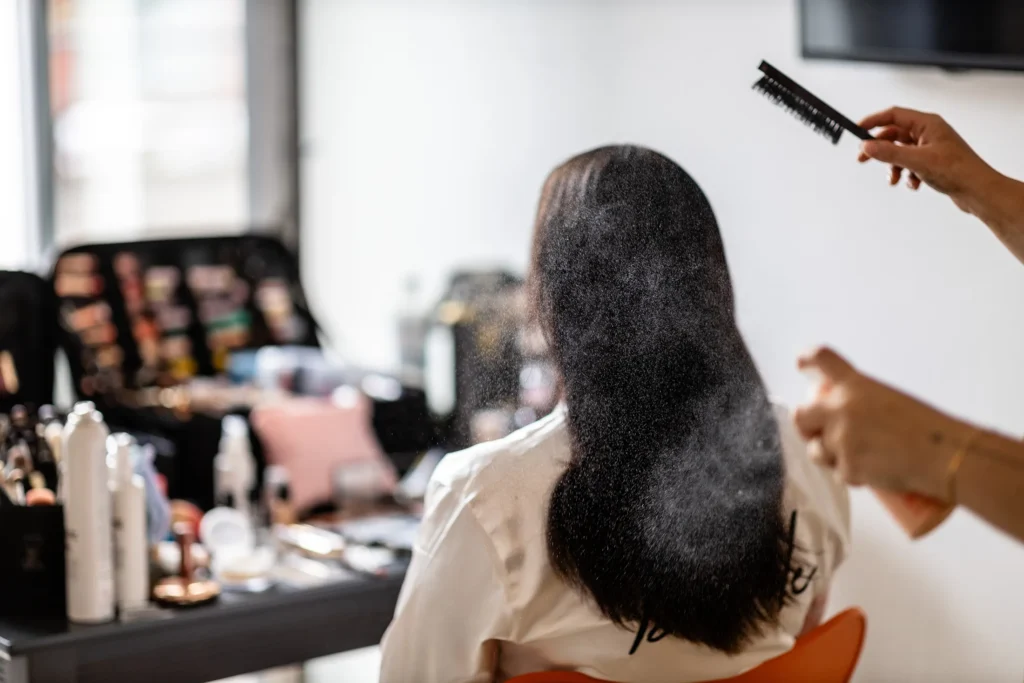Hochzeitsfotograf Bernkastel Trier - Braut von hinten auf dem Stuhl sitzend, während Haarspray aufgesprüht wird.