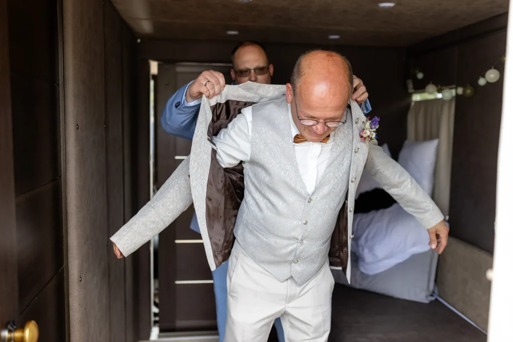 Hochzeitsfotograf Bernkastel Trier - Schwiegersohn hilft dem Bräutigam beim Getting Ready in das Sakko.