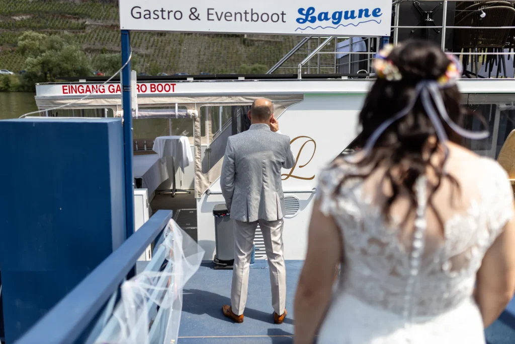 Hochzeitsfotograf Bernkastel Trier - First Look: Der Bräutigam steht mit dem Rücken zur Braut vor dem Event-Boot und wartet darauf, dass die Braut zu ihm kommt, damit er sie zum ersten Mal im Brautkleid sehen kann.