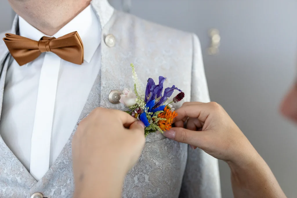 Hochzeitsfotograf Bernkastel Trier - Nahaufnahme, wie die Ansteckblume des Bräutigams gerade gerichtet wird
