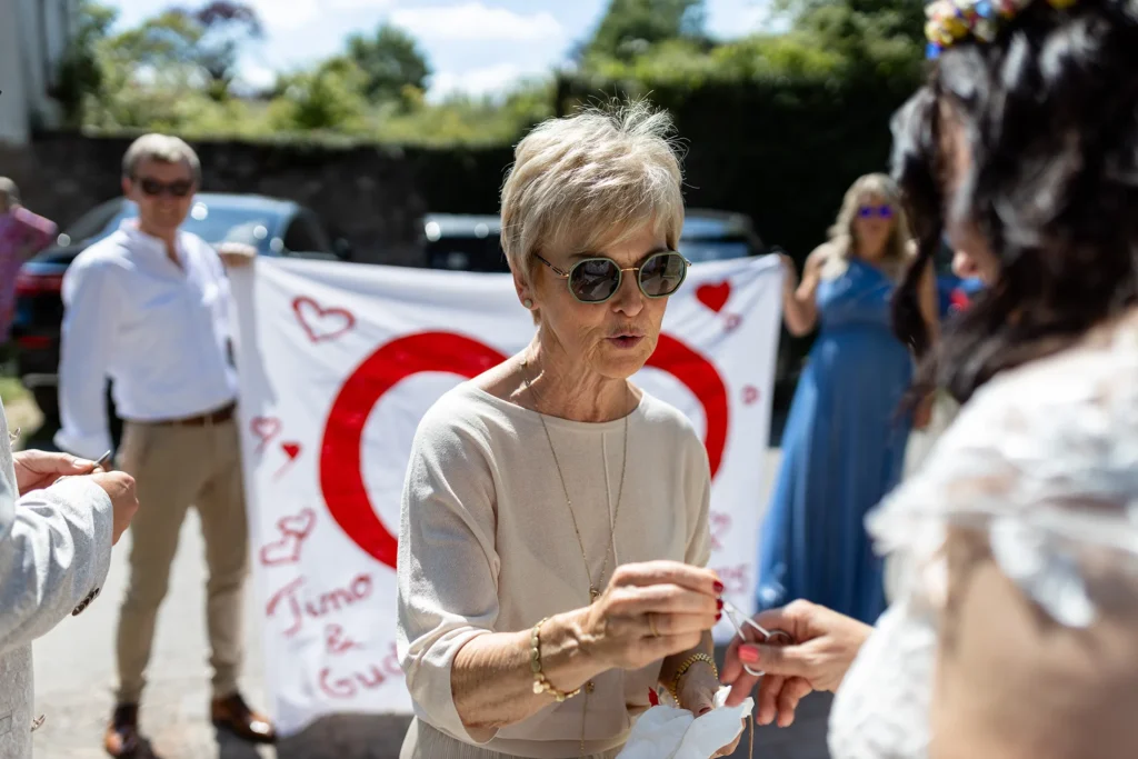 Hochzeitsfotograf Bernkastel Trier - Gast übergibt Nagelschere zum traditionellen Bettlaken durchschneiden auf einer Hochzeit.