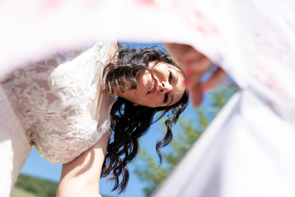 Hochzeitsfotograf Bernkastel Trier - Nette Perspektive, wie die Braut das Bettlaken durchschneidet.