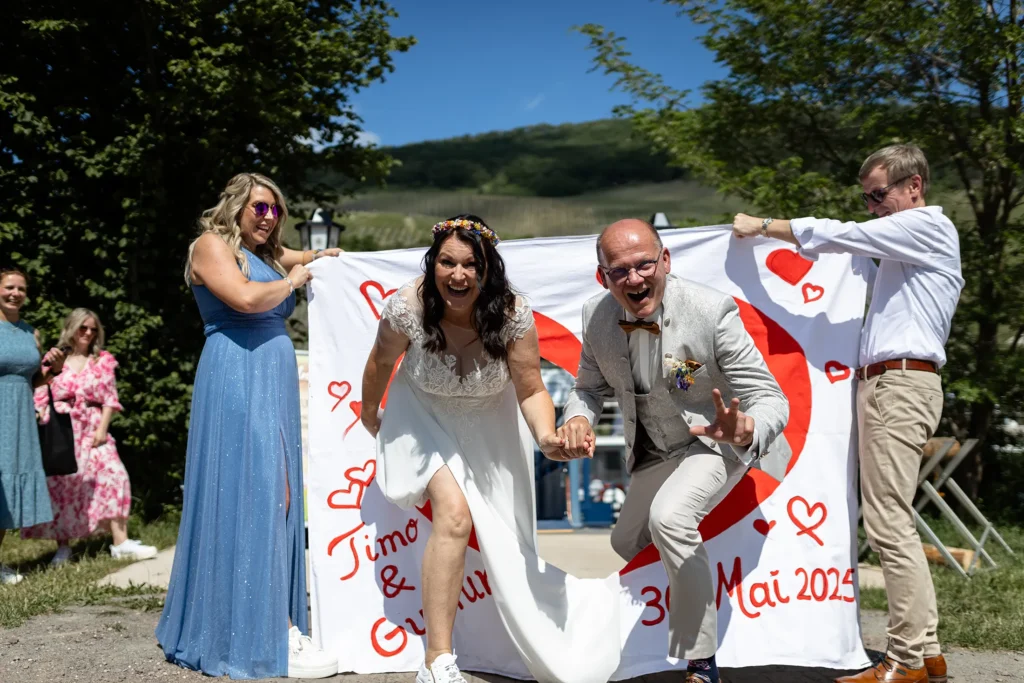 Hochzeitsfotograf Bernkastel Trier - Brautpaar steigt durch das durchgeschnittene Bettlaken.