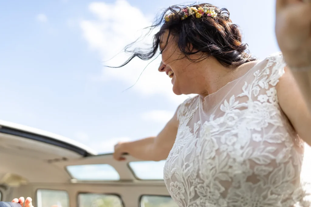 Hochzeitsfotograf Bernkastel Trier - Die Haare der Braut flattern im Wind, weil sie während der Fahrt ihren Kopf aus dem Dachfenster des T1 Bulli hält. Nette Perspektive.