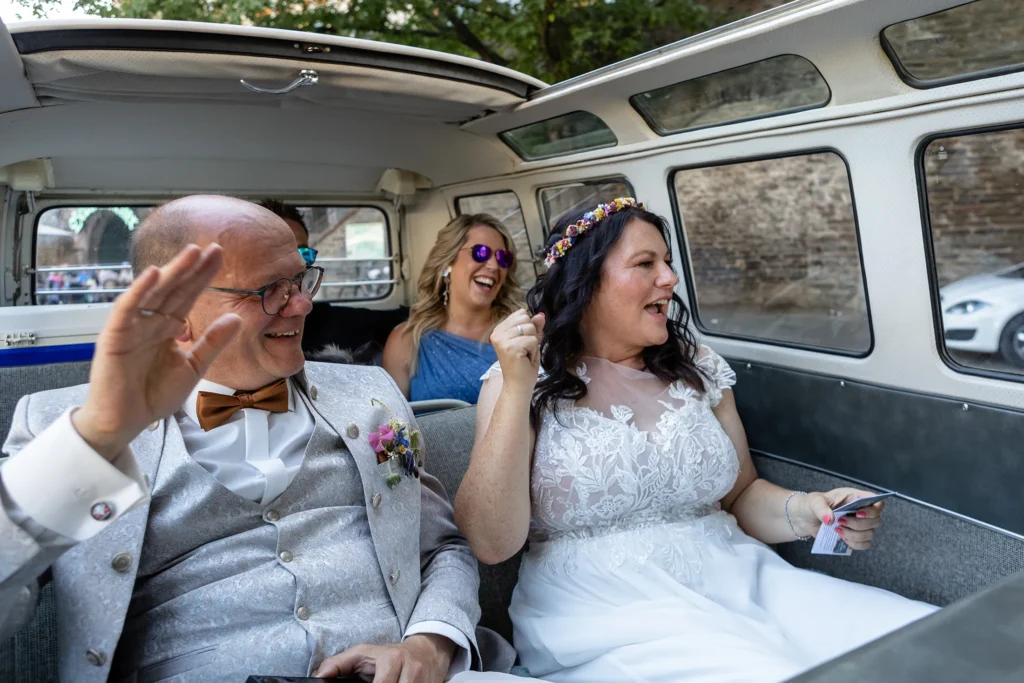 Hochzeitsfotograf Bernkastel Trier - Momentaufnahme: das Brautpaar jubelt bei der Fahrt im Volkswagen T1 Bulli auf dem Rückweg von der Weinprobe in den Weinbergen.