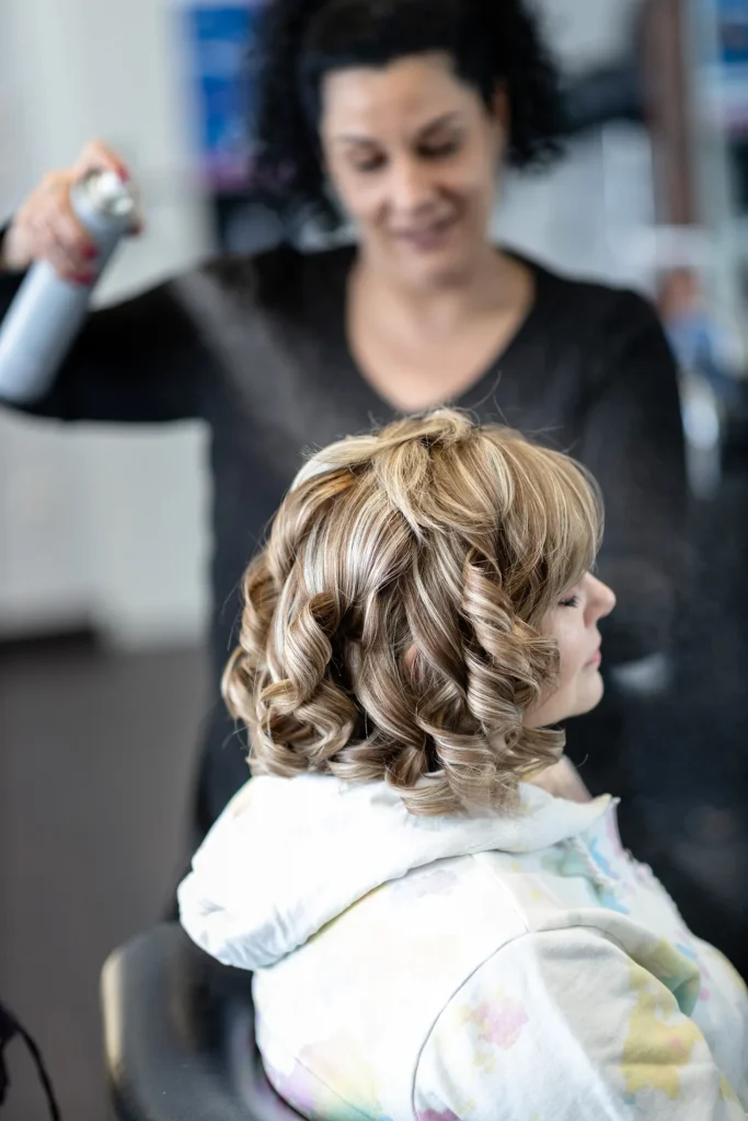 Hochzeitsfotograf Luxemburg - Friseurin sprüht der Braut Haarspray in die Haare.