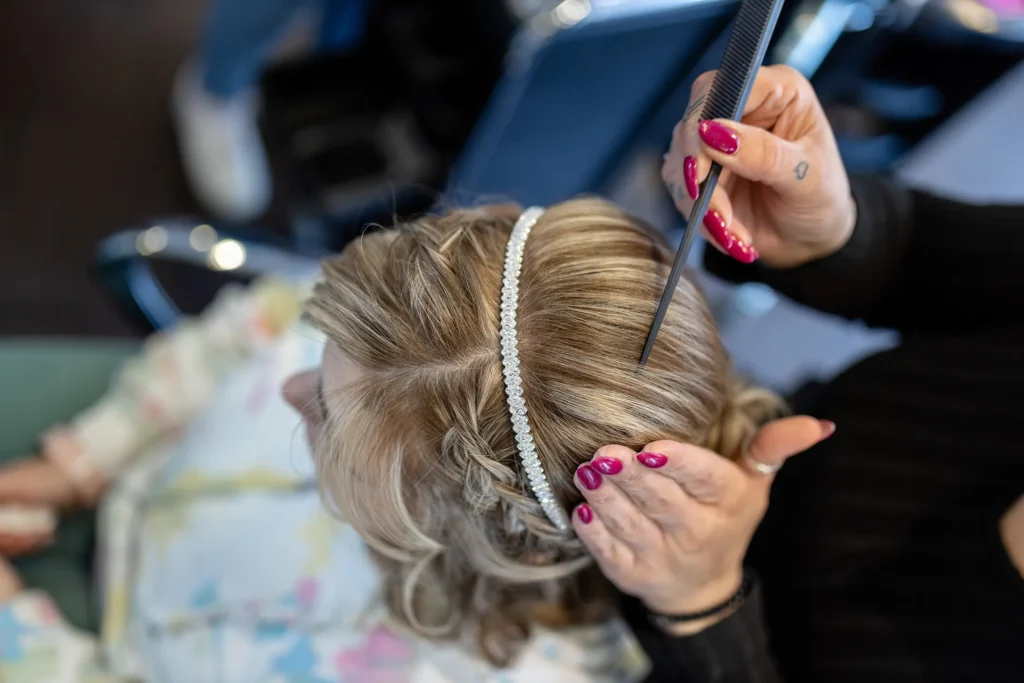 Hochzeitsfotograf Luxemburg - Nahaufnahme: die Friseurin steckt mit einem Kamm die Haare ab.
