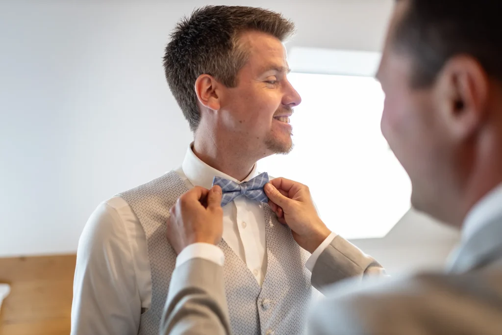 Hochzeitsfotograf Luxemburg - Trauzeuge richtet dem Bräutigam beim Getting Ready die Fliege.