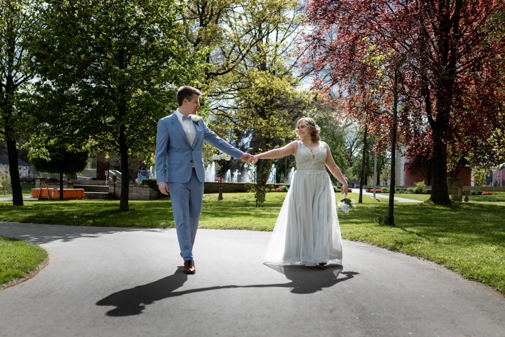 Hochzeitsfotograf Luxemburg - Brautpaar hält beim Spazierengehen Händchen und guckt sich verliebt an. Emotionale Aufnahme