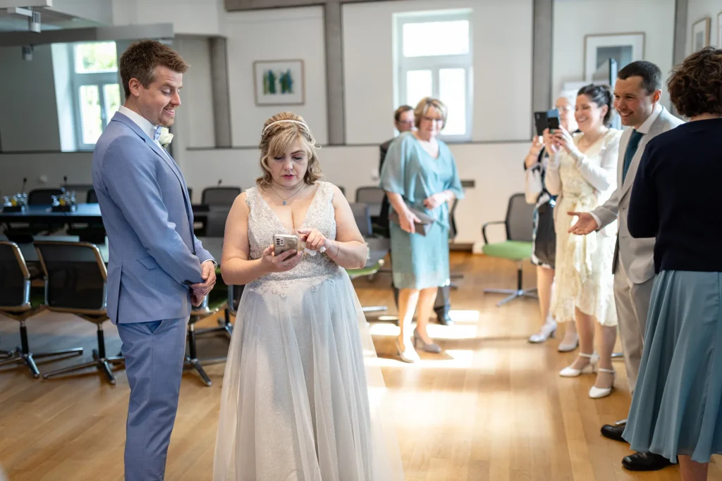 Hochzeitsfotograf Luxemburg - Die Braut checkt im Wartesaal des Standesamts in Diekirch noch schnell ihr Smartphone, bevor die Trauung beginnt.