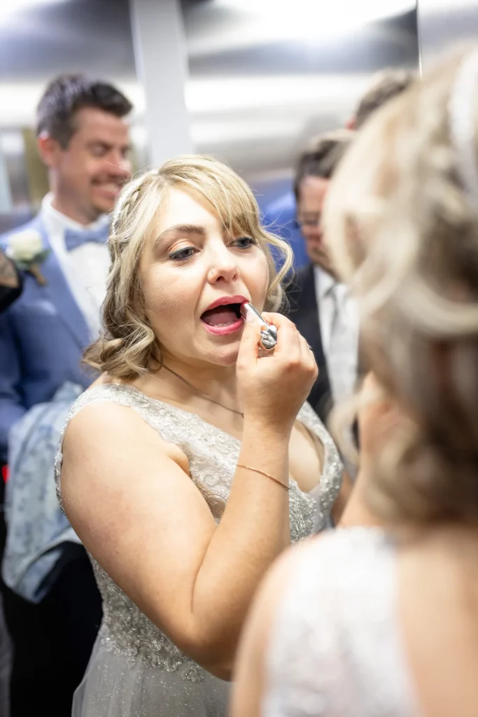 Hochzeitsfotograf Luxemburg - Im Aufzug des Standesamts zieht sich die Braut an einem Spiegel des Aufzugs den Lippenstift nach auf dem Weg nach draussen.