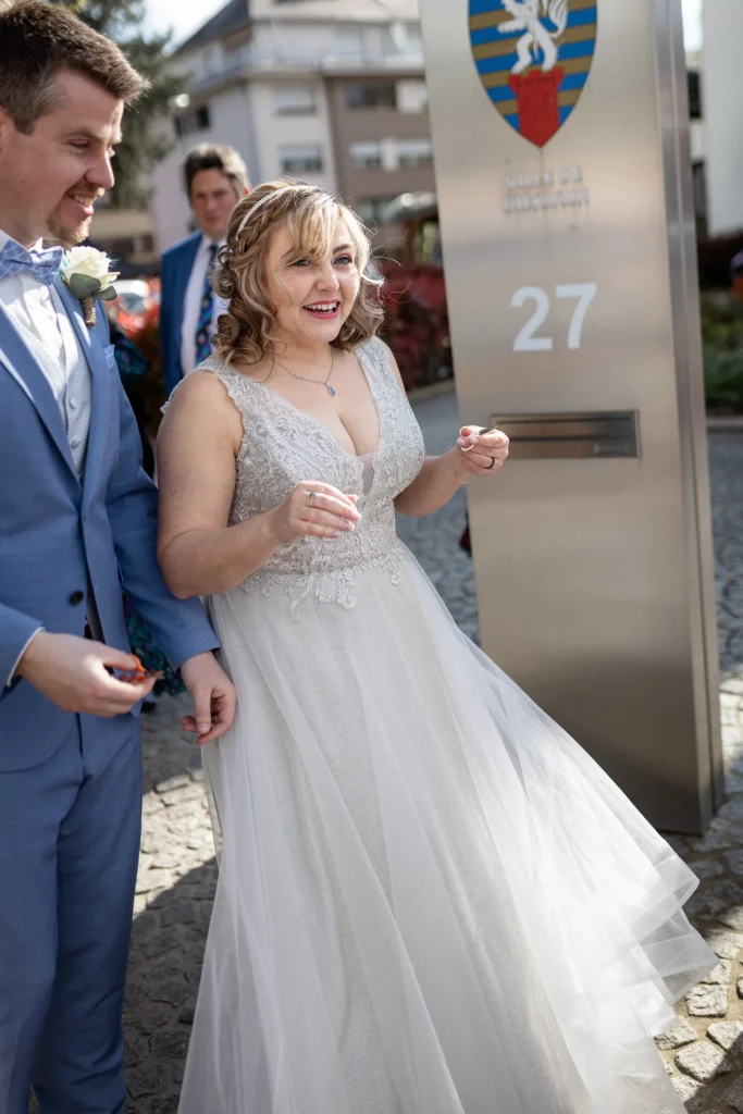Hochzeitsfotograf Luxemburg - Vor dem Standesamt in Diekirch sehen wir die emotionale Reaktion des Brautpaars als sie mit dem klassischen Bettlaken durchschneiden überrascht werden.