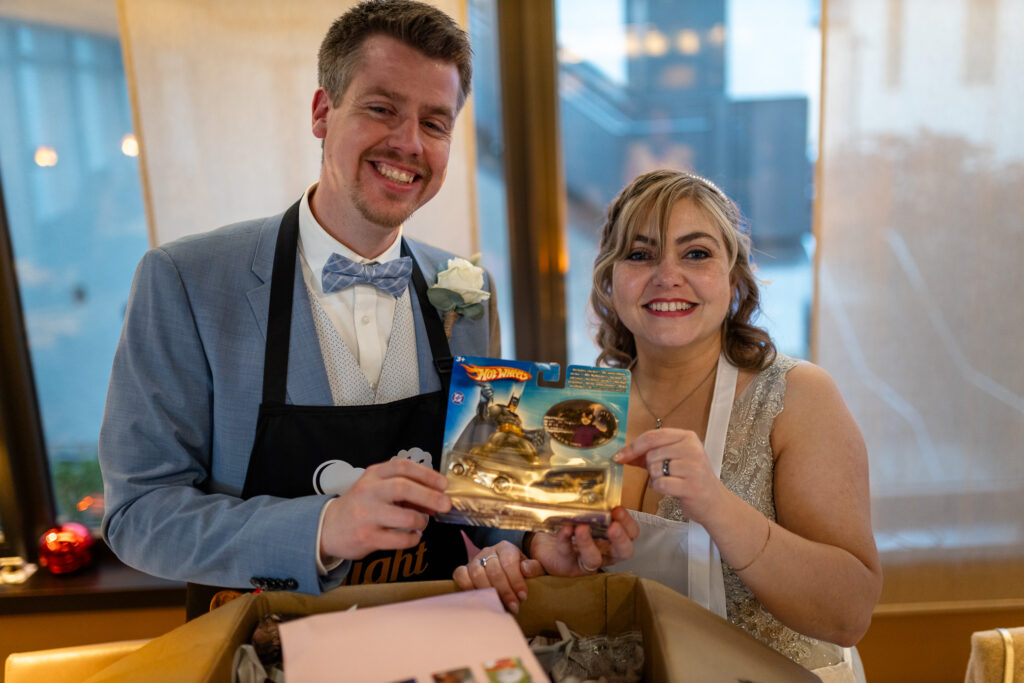 Hochzeitsfotograf Luxemburg - Brautpaar hält ein Geschenk direkt in die Kamera und freut sich.