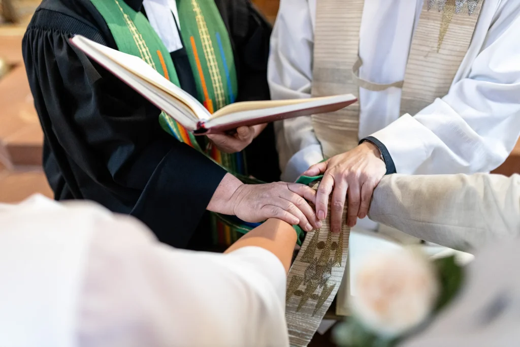 Hochzeitsfotograf Merzig Trier - Nahaufnahme der Segnung bei der Trauung in der Kirche: Man sieht nur die Hände des Brautpaars und des Pfarrers.