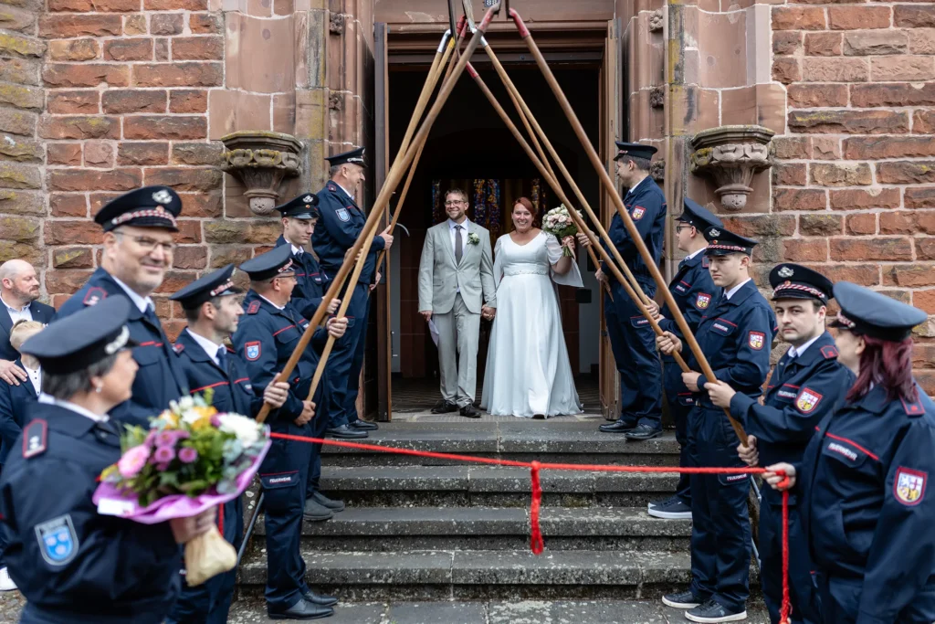 Hochzeitsfotograf Merzig Trier - Die Feuerwehr empfängt das Brautpaar, das gerade durch die Tür aus der Kirche kommt.