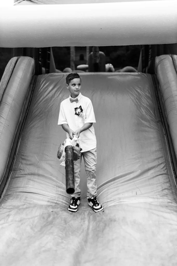 Hochzeitsfotograf Merzig Trier - Ein Kind macht mit einem Laubbläser die Hüpfburg für die Hochzeitsgäste sauber