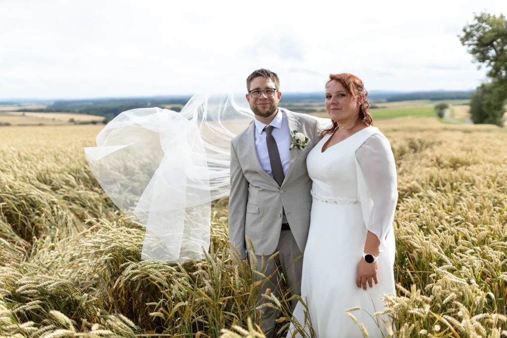 Hochzeitsfotograf Merzig Trier - Der Schleier der Braut wird beim Brautpaar Shooting durch den Wind nach oben geweht - witziges Bild mit Charme.