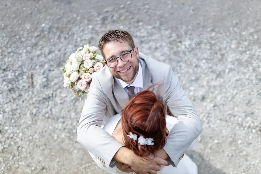 Hochzeitsfotograf Merzig Trier - Der glückliche Bräutigam von oben fotografiert, während er seine Braut im Arm hält.