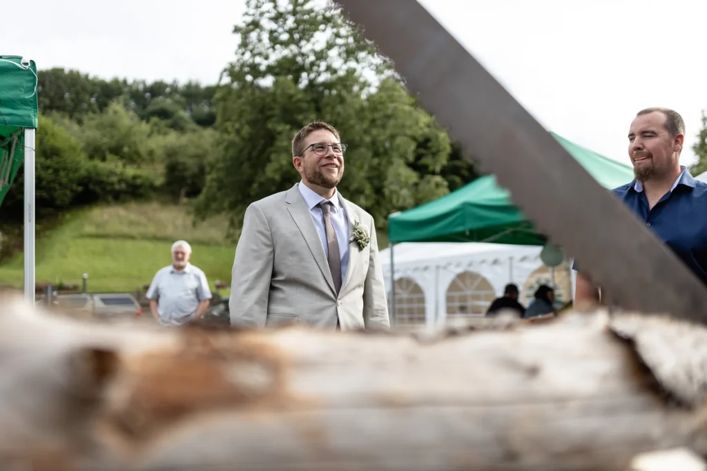 Hochzeitsfotograf Merzig Trier - Der Bräutigam schaut sich gerade den Baumstamm an, den er gleich mit seiner Frau sägen muss. Ungewöhnliche Perspektive.