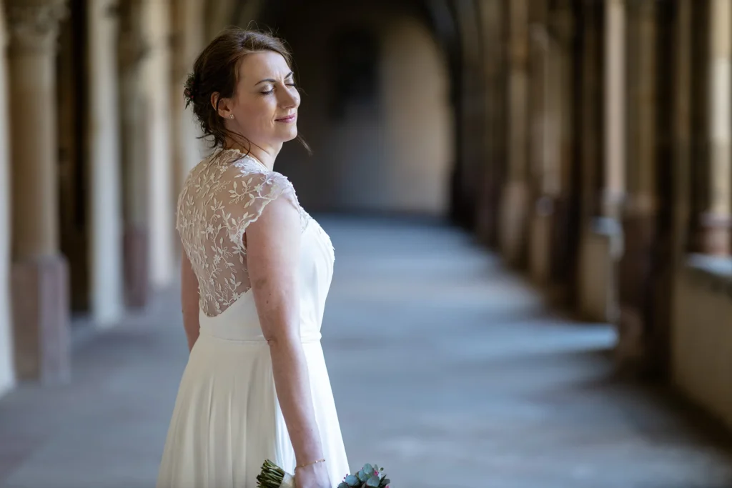 Hochzeitsfotograf Trier Luxemburg - Die Braut steht im Gang des Kreuzgartens des Trier Doms und geniesst den Augenblick