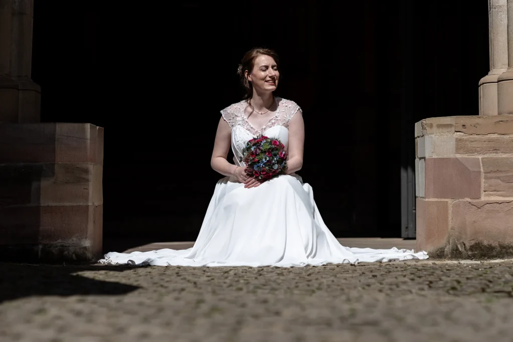 Hochzeitsfotograf Trier Luxemburg - Braut posiert in der Sonne im Kreuzgarten im Trier Dom für das Foto.