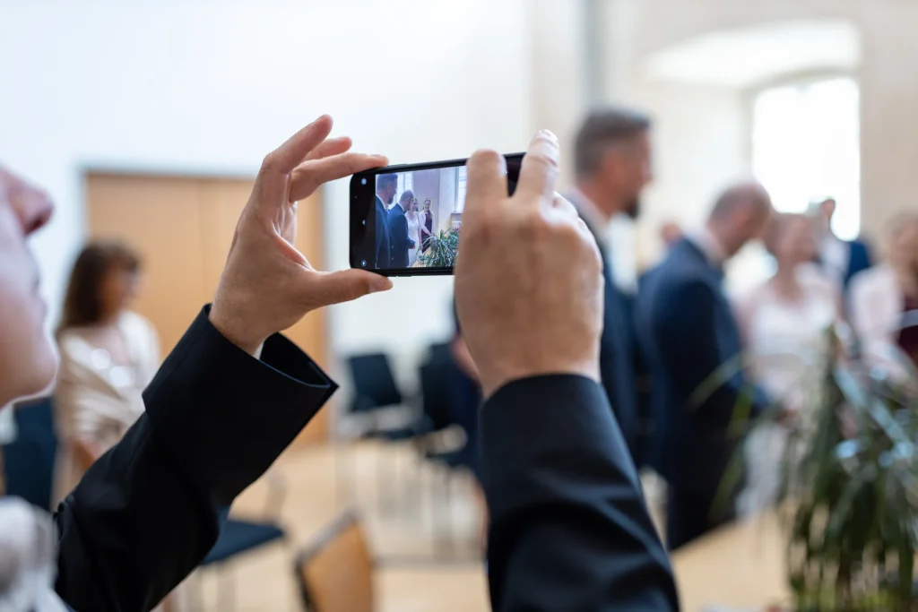 Hochzeitsfotograf Trier Luxemburg - Ein Gast fotografiert die Trauung mit dem Smartphone.
