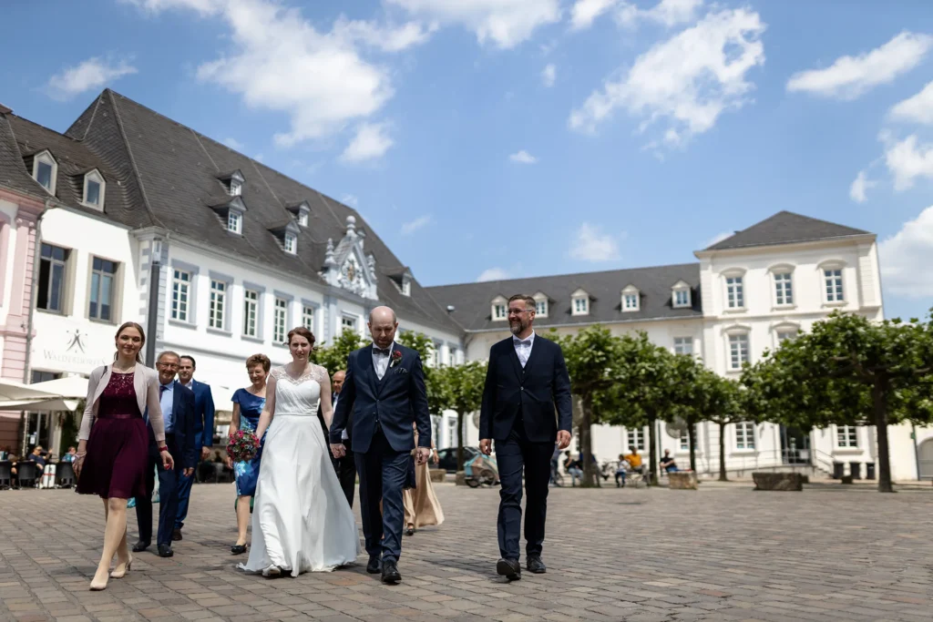 Hochzeitsfotograf Trier Luxemburg - Hochzeitsgesellschaft geht über den Dom Vorplatz auf dem Weg zur nächsten Location