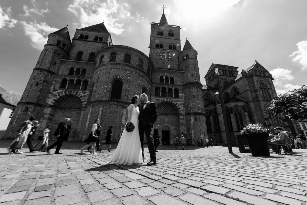 Hochzeitsfotograf Trier Luxemburg - Brautpaarfoto direkt nach Auszug aus dem Standesamt vor dem Trier Dom. Weitwinkel, schwarz-weiss