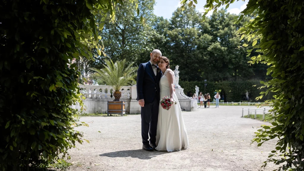 Hochzeitsfotograf Trier Luxemburg - Brautpaarfoto im Palastgarten in Trier: Das Paar küsst sich auf dem Weg und wird von Hecken eingerahmt.