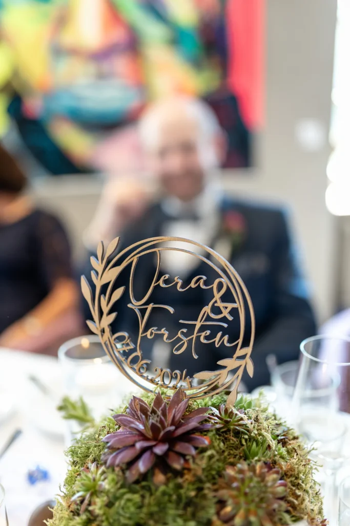 Hochzeitsfotograf Trier Luxemburg - Detailfoto der Dekoration der Hochzeit. Im Hintergrund unscharf: der Bräutigam.