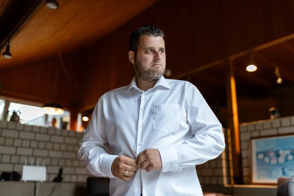 Hochzeitsfotograf Trier Luxemburg - Ready: Der Bräutigam knüpft sich das weisse Hemd zu.