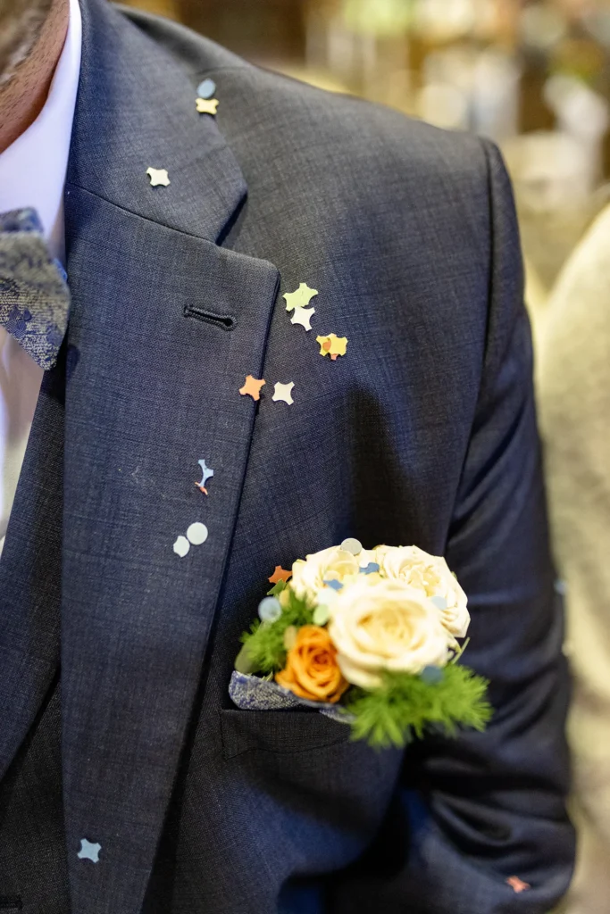 Hochzeitsfotograf Trier Luxemburg - Detail Aufnahme des Sakkos des Bräutigams. Vorher wurde Konfetti gestreut, man sieht die bunten Konfetti Stücke deutlich auf dem Sakko.