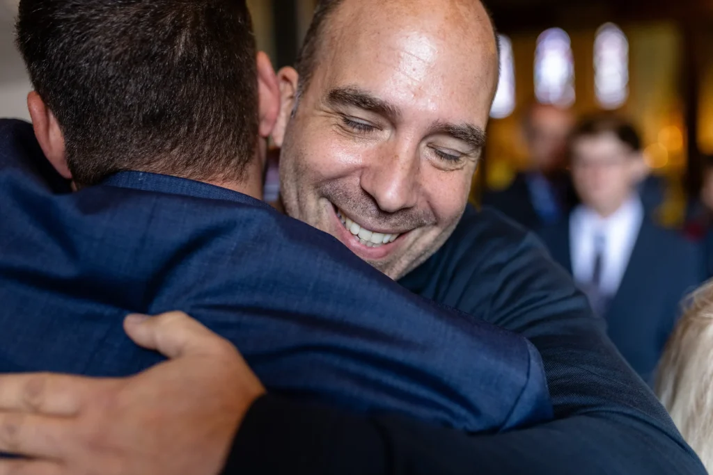 Hochzeitsfotograf Trier Luxemburg - Nahaufnahme: Ein Freund gratuliert dem Bräutigam. Man sieht sein Gesicht und den Rücken des Bräutigams.