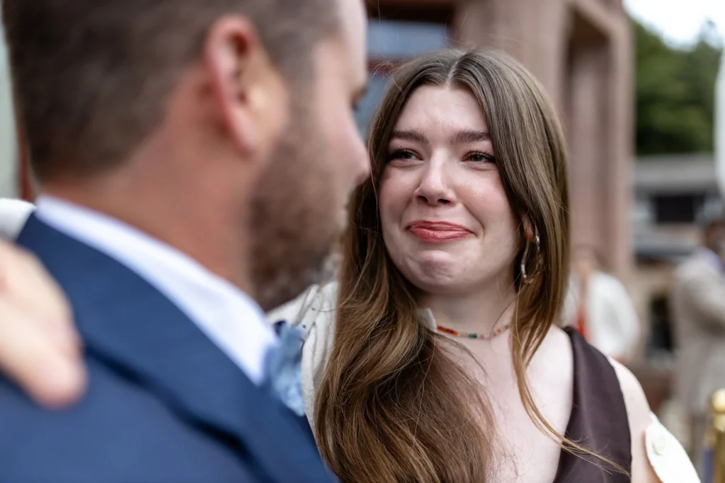 Hochzeitsfotograf Trier Luxemburg - Die Cousine des Bräutigams hält die Tränen zurück, während sie den Bräutigam anschaut.