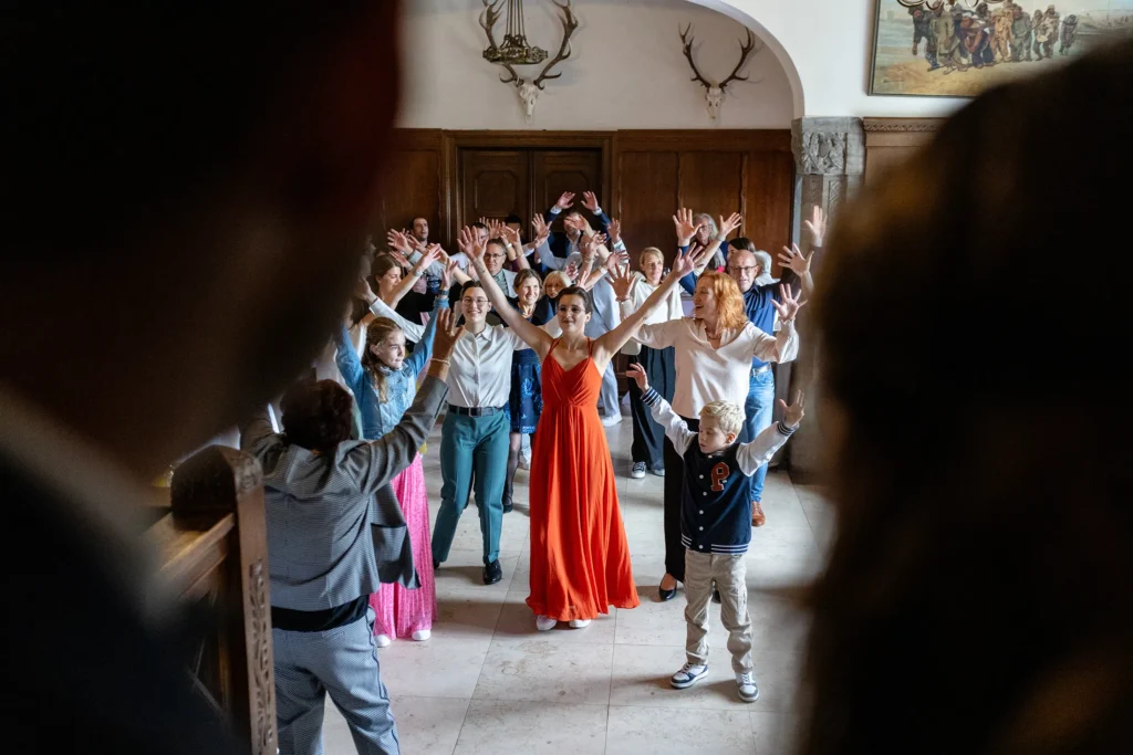 Hochzeitsfotograf Trier Luxemburg - Flashmob für das brautpaar. Auf der Tanzfläche tanzen viele Gäste als Überraschung für das Hochzeitspaar. Interessante Perspektive, weil durch die Lücke zwischen den Köpfen des Brautpaars durch fotografiert wurde.