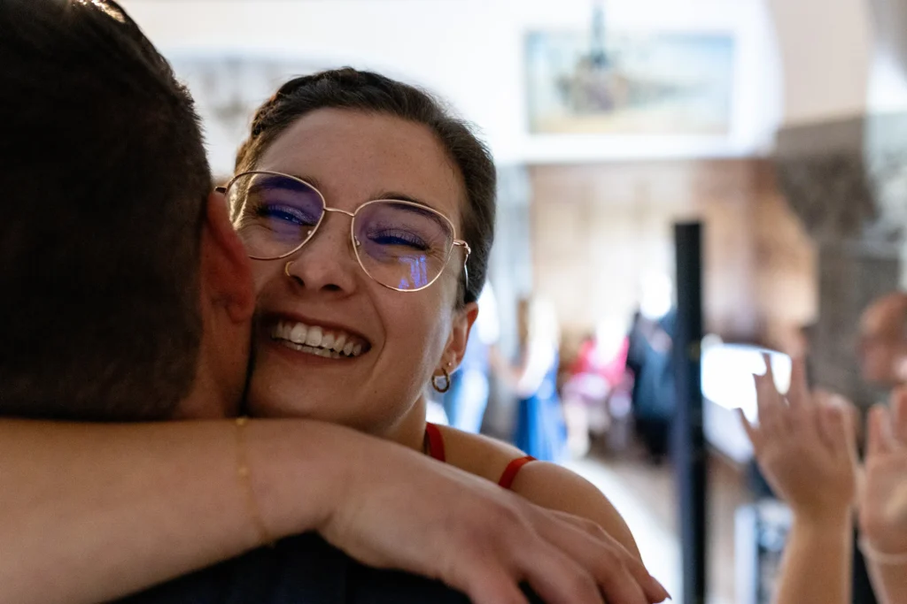 Hochzeitsfotograf Trier Luxemburg - Trauzeugin Nahaufnahme, wie sie den Bräutigam nach einem Familien-Flashmob für das Paar in den Arm nimmt.