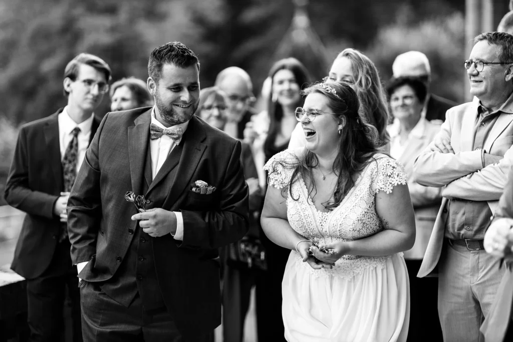 Hochzeitsfotograf Trier Luxemburg - Momentaufnahme von Braut und Bräutigam beim geschenke-Dart-Spiel: Die Braut lacht sehr herzlich. Schwarz-weiss Foto.