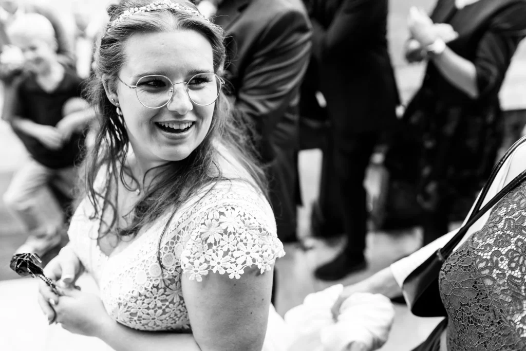 Hochzeitsfotograf Trier Luxemburg - Die Braut lächelt einen anderen Gast an, während des Geschenke-Dart-Spiels. Sie hält die Dartpfeile in der Hand.