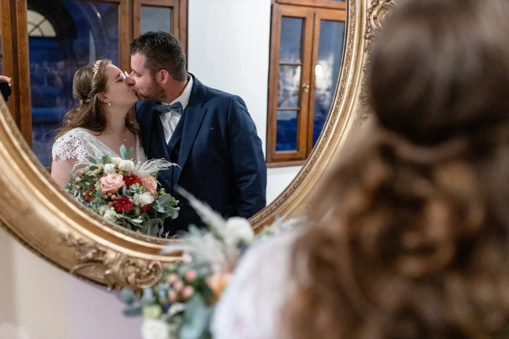 Hochzeitsfotograf Trier Luxemburg - Brautpaar steht vor einem goldenen Spiegel und küsst sich.