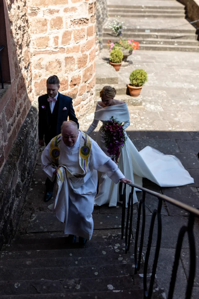 Hochzeitsfotograf Trier Luxemburg - Der Pfarrer geht voraus und hinter ihm folgt das Brautpaar auf dem Weg zur Kapelle