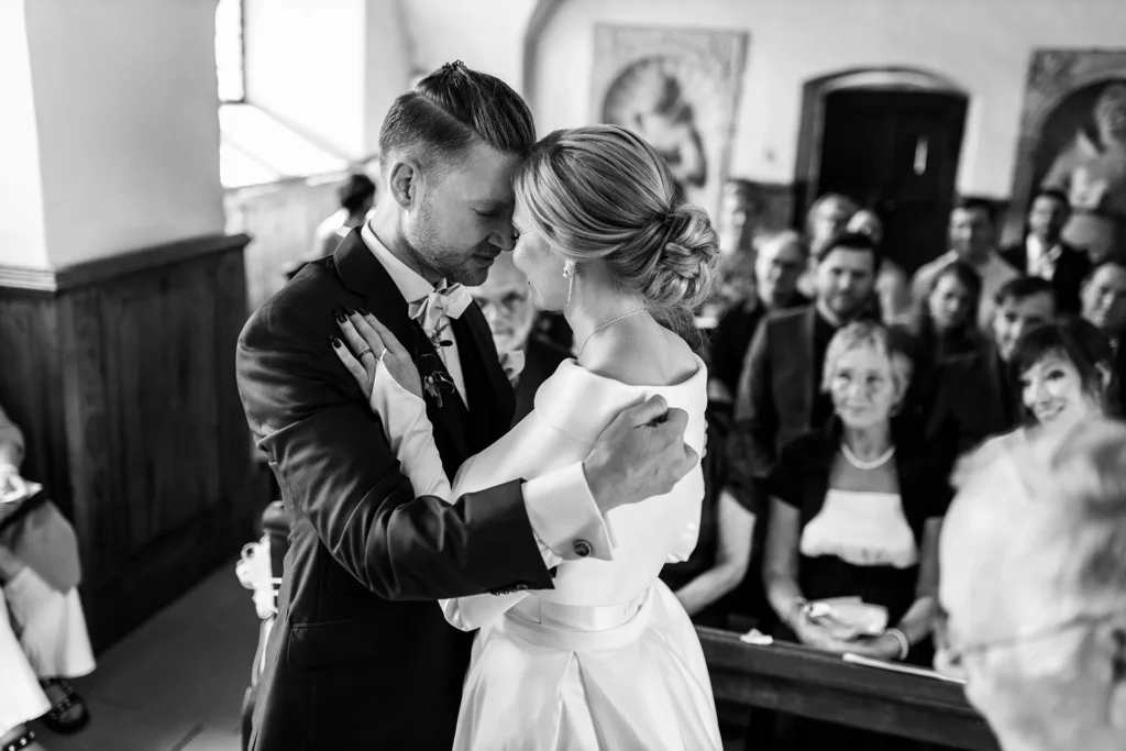 Hochzeitsfotograf Trier Luxemburg - Das Brautpaar umarmt sich in der Kapelle von Schloss Hamm vor der Hochzeitsgesellschaft, die im Hintergrund des Fotos unscharf zu sehen ist.