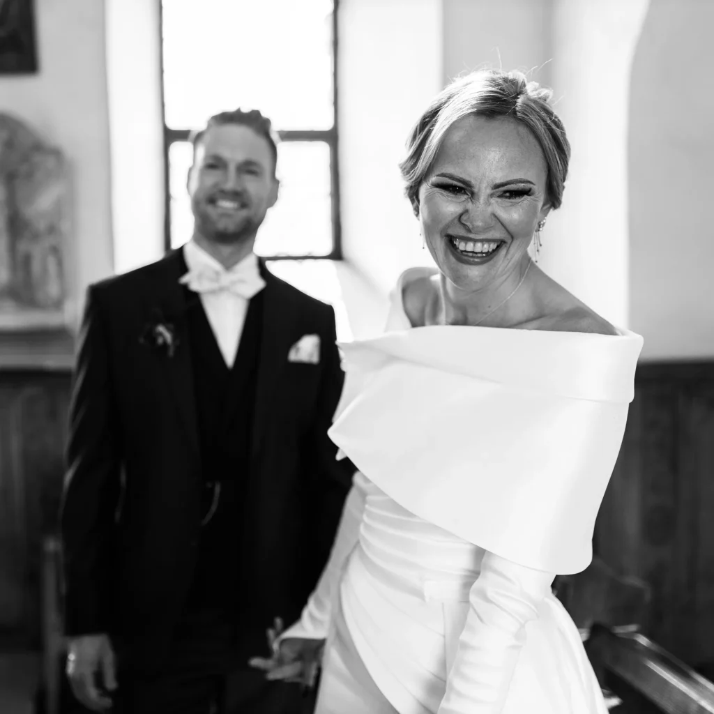 Hochzeitsfotograf Trier Luxemburg - Lachende Braut und im Hintergrund unscharf der lachende Bräutigam. Emotionale schwarz-weiss Aufnahme