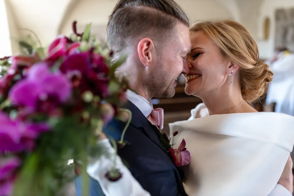 Hochzeitsfotograf Trier Luxemburg - Braut und Bräutigam küssen sich nach der Trauung. Mit im Bild vorne links: der bunte Brautstrauss